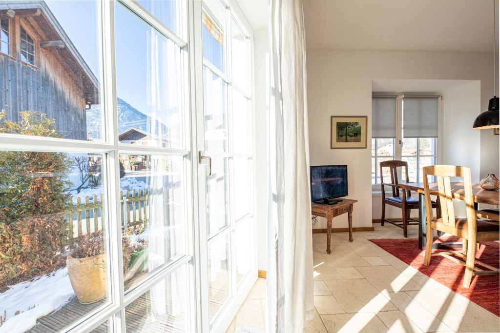 Wohnbereich mit Fernseher, Esstisch und Ausblick in Ferienwohnung in Garmisch-Partenkirchen