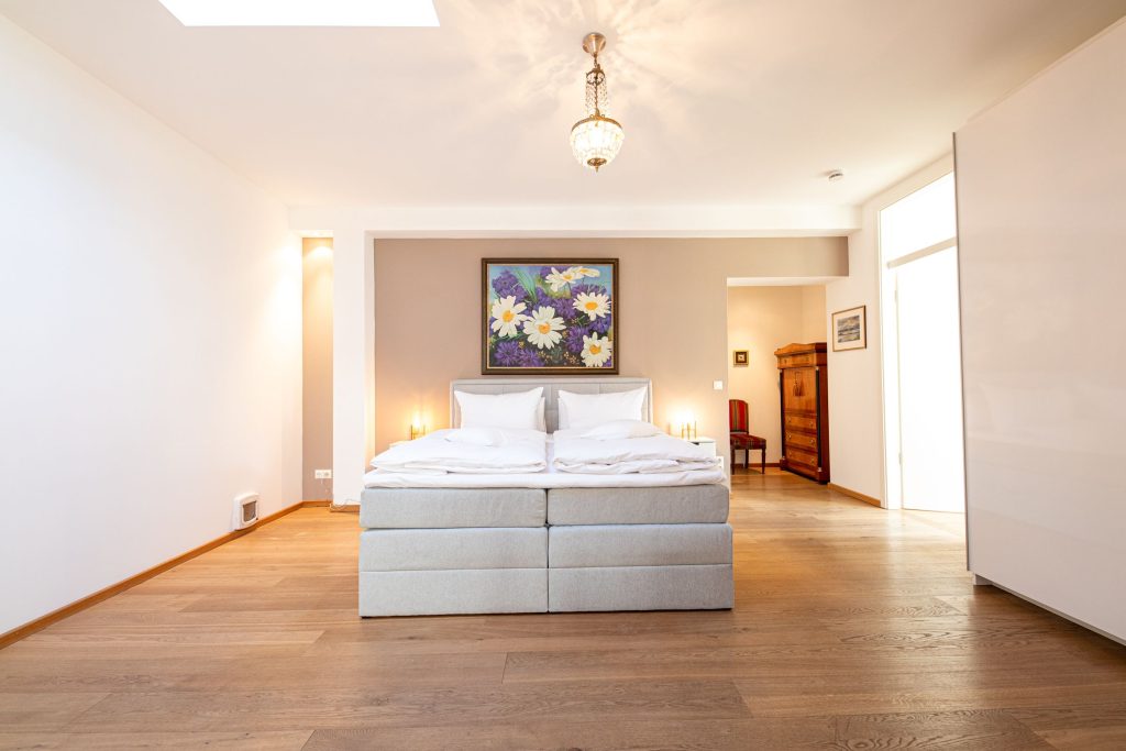 Doppelbett mit Bild von Blumen und Hängelampe in Ferienwohnung in Garmisch-Partenkirchen