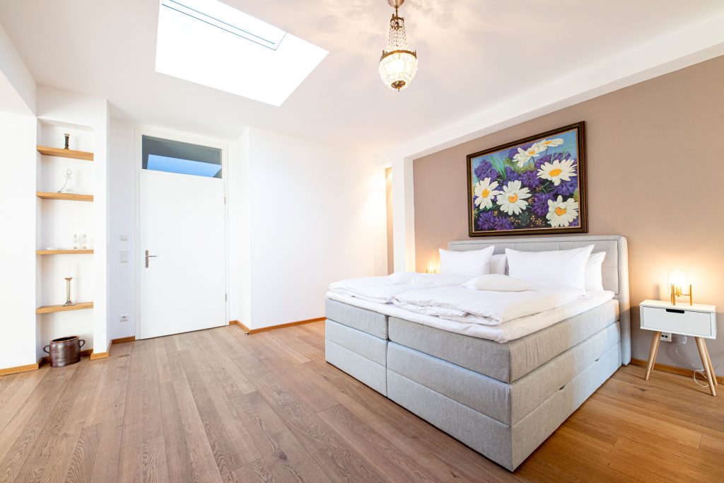 Schlafzimmer mit Doppelbett in hellgrau mit Blumenbild und Beistelltischen in Ferienwohnung in Garmisch-Partenkirchen