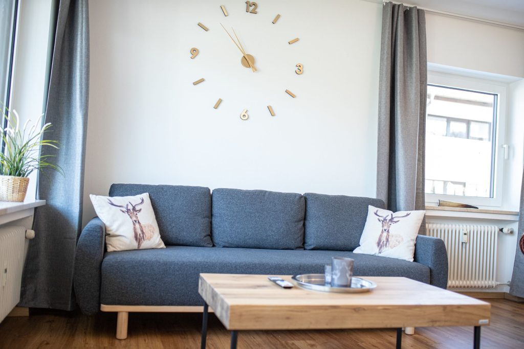 graues Sofa mit Uhr in Ferienwohnung in Garmisch-Partenkirchen