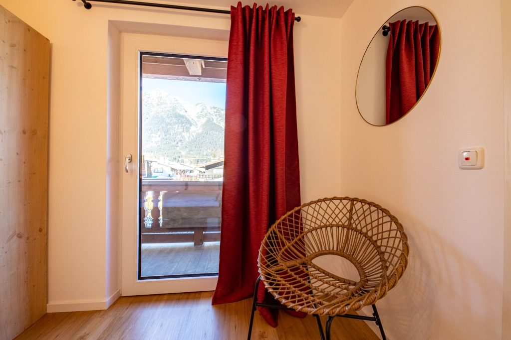 Schlafzimmer mit roter Gardine in Ferienwohnung in Garmisch-Partenkirchen