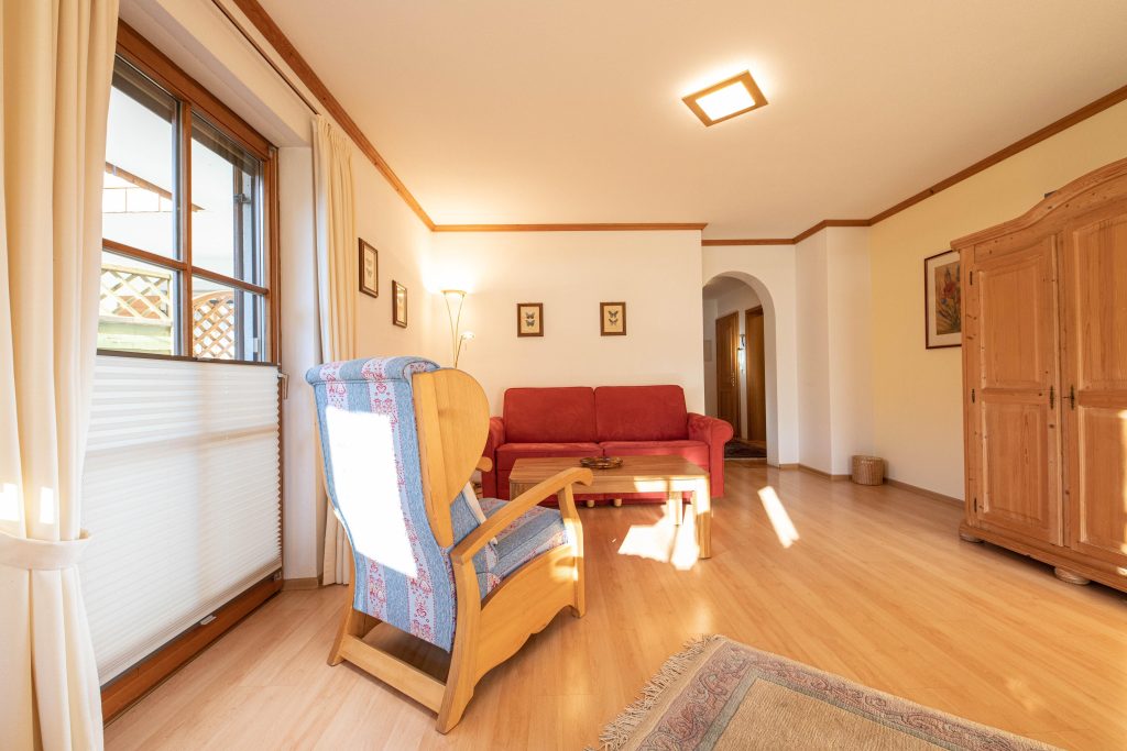 Wohnbereich mit einem blau gemusterten Stuhl  in Ferienwohnung in Garmisch-Partenkirchen