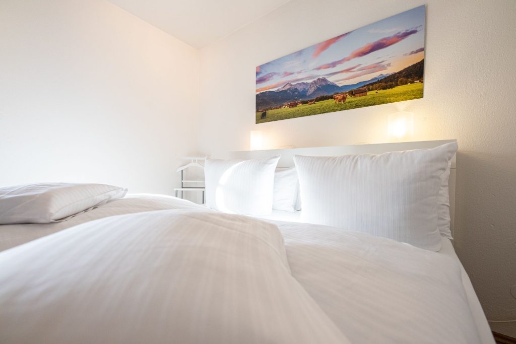 Weiches Bett mit Bergbild in Ferienwohnung in Garmisch-Partenkirchen