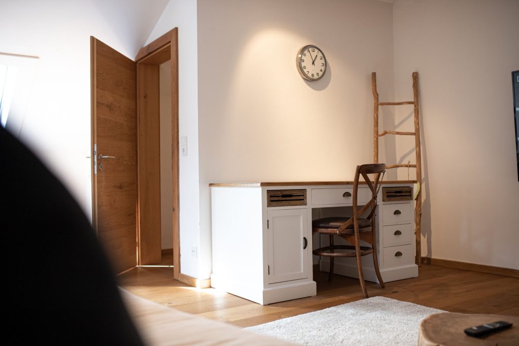 Wohnbereich mit einem Holzstuhl an einem Tisch mit vielen Schubladen in Ferienwohnung in Garmisch-Partenkirchen