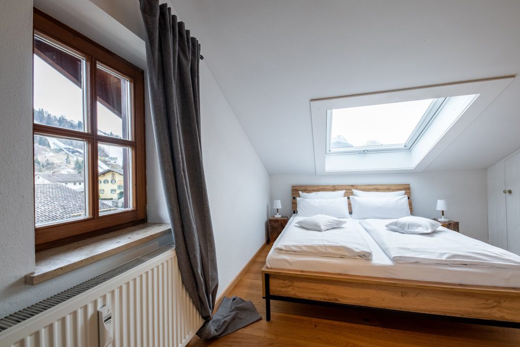 Schlafzimmer mit einem Doppelbett und zwei Fenstern in Ferienwohnung in Garmisch-Partenkirchen