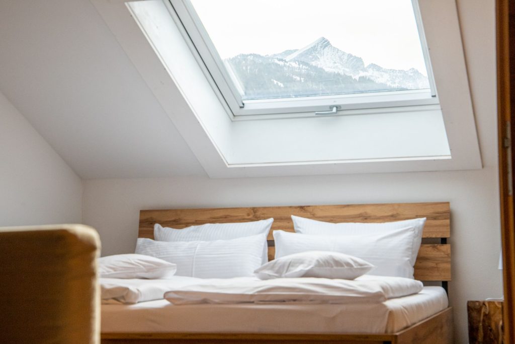 Schlafzimmer mit einem Holz-Doppelbett mit Dachfenster in Ferienwohnung in Garmisch-Partenkirchen