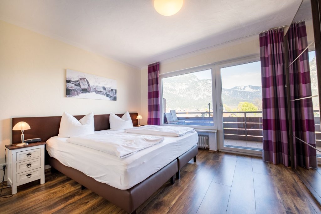 Schlafzimmer mit braunem Holzboden in Ferienwohnung in Garmisch-Patenkirchen